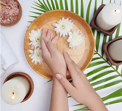 woman soaking her hands bowl water flowers spa treatment product female feet hand spa massage pebble perfumed flowers water candles relaxation flat lay top view
